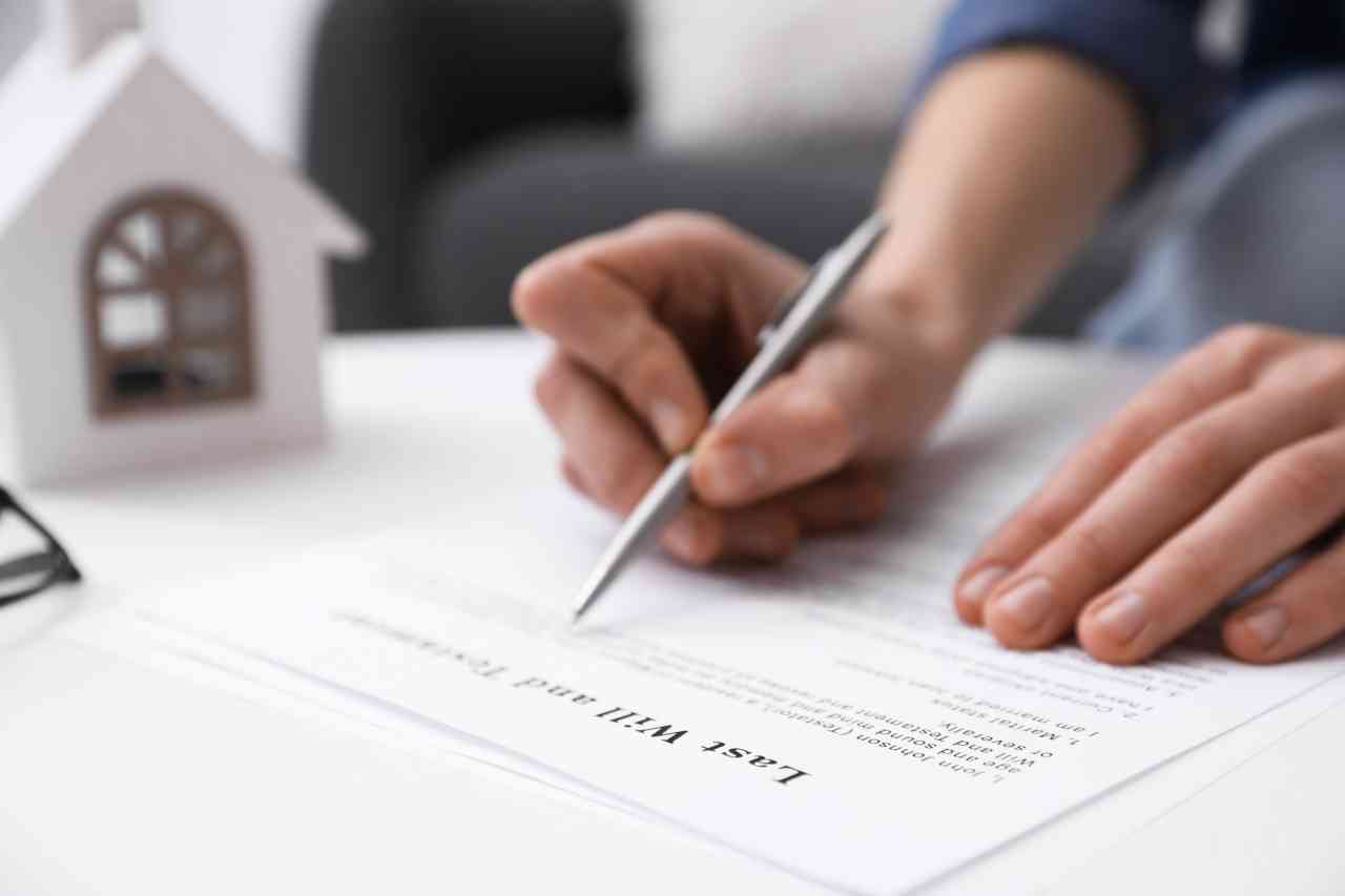 Woman signing Last Will and Testament at white table indoors, closeup